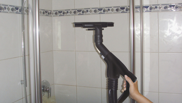 Reinigung der Glaswand von einer Dusche mit einem Dampfsauger