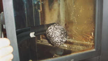 Reinigung von der Glastür eines Kachelofens mit einem Dampfsauger